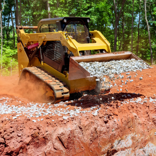 A skid steer dumping gravel out of its bucket